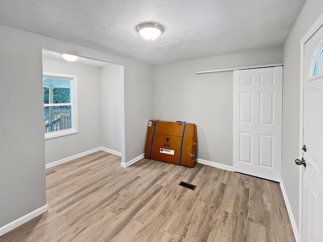 interior space featuring light hardwood / wood-style floors, a textured ceiling, and a closet