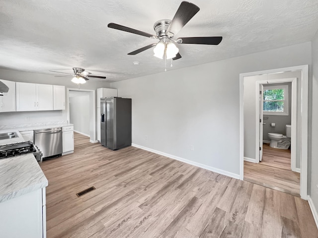 kitchen with white cabinetry, ceiling fan, light hardwood / wood-style flooring, a textured ceiling, and appliances with stainless steel finishes