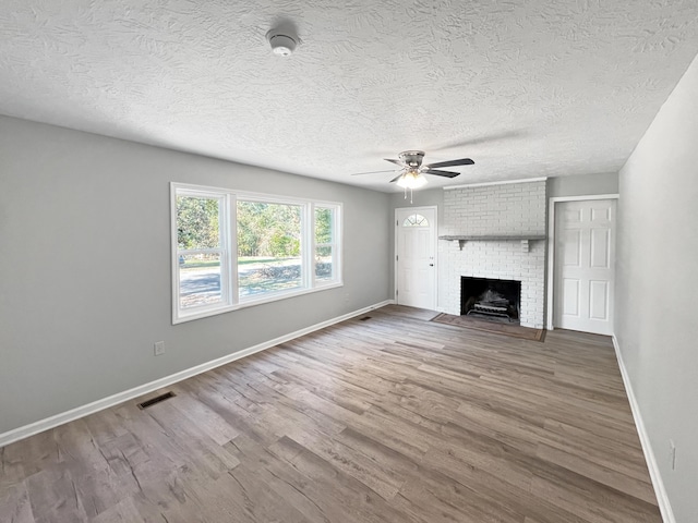 unfurnished living room featuring a textured ceiling, ceiling fan, wood-type flooring, and a fireplace