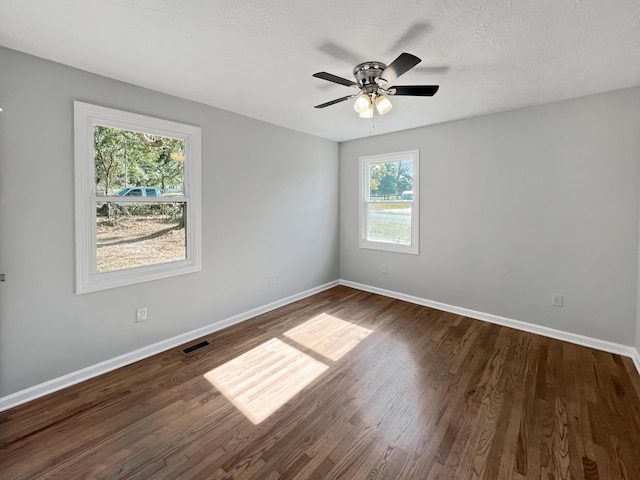 spare room with ceiling fan, a healthy amount of sunlight, and dark hardwood / wood-style flooring