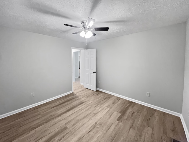 empty room featuring ceiling fan, light hardwood / wood-style flooring, and a textured ceiling