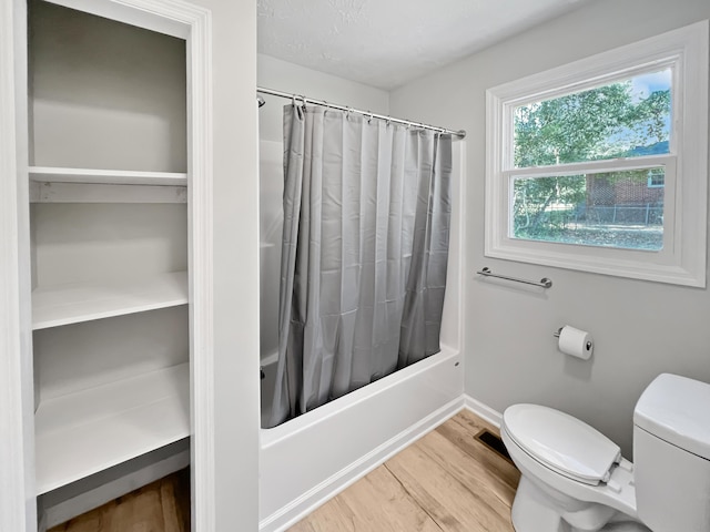 bathroom with shower / bath combination with curtain, hardwood / wood-style flooring, and toilet