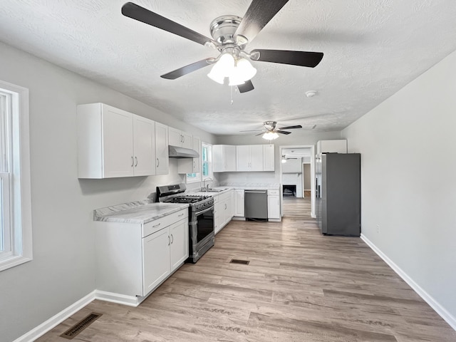 kitchen with a textured ceiling, stainless steel appliances, sink, light hardwood / wood-style floors, and white cabinetry