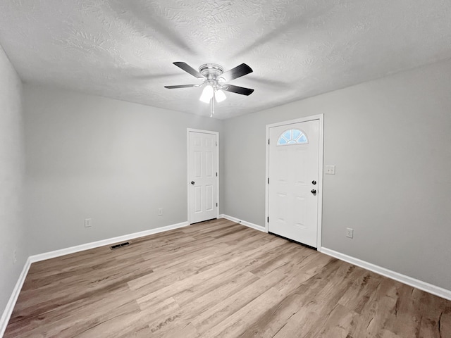 entryway featuring ceiling fan, light hardwood / wood-style floors, and a textured ceiling