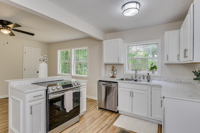 kitchen featuring white cabinets, sink, light hardwood / wood-style flooring, a textured ceiling, and stainless steel appliances