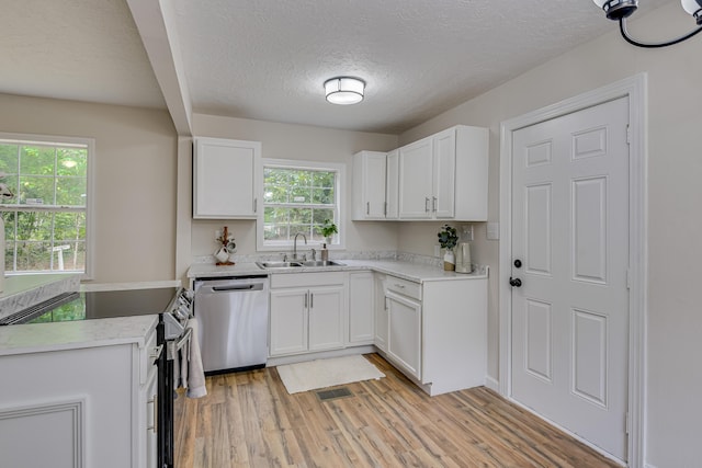 kitchen with appliances with stainless steel finishes, light wood-type flooring, a textured ceiling, sink, and white cabinetry