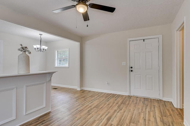 interior space with a textured ceiling, ceiling fan with notable chandelier, and light hardwood / wood-style floors