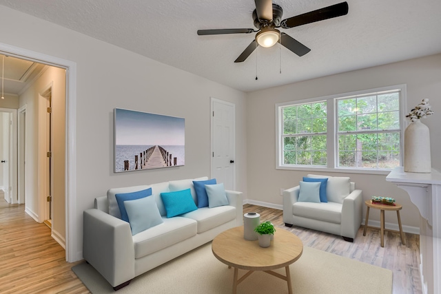 living room with ceiling fan, light hardwood / wood-style floors, and a textured ceiling