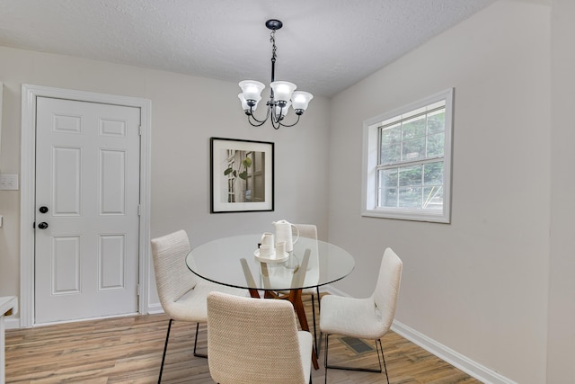 dining space with a chandelier, a textured ceiling, and light hardwood / wood-style flooring