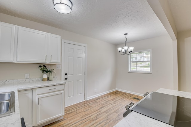 kitchen with white cabinets, a notable chandelier, light hardwood / wood-style floors, and hanging light fixtures