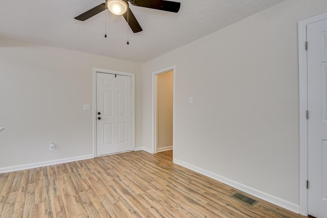 empty room with ceiling fan, light hardwood / wood-style floors, and a textured ceiling