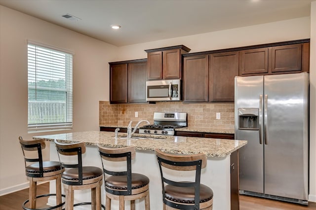 243 Quick Silver Ct, Graniteville, SC 29829 - kitchen featuring stainless steel appliances, tasteful backsplash, dark brown cabinets, light stone counters, and a center island with sink