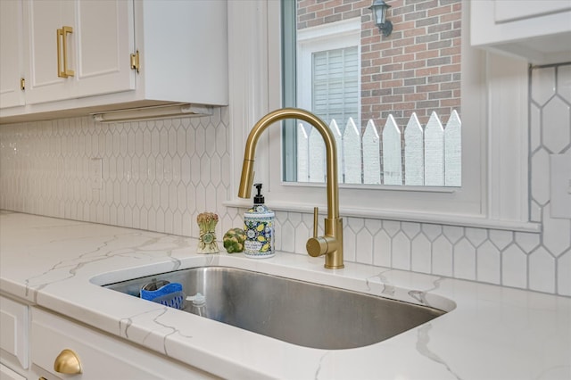 820 Barrett Ln, Augusta, GA 30909 - kitchen view of a sink, tasteful backsplash, white cabinetry, and light stone counters