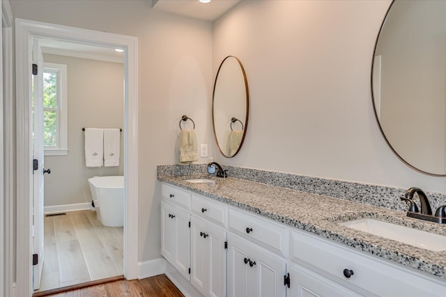 820 Barrett Ln, Augusta, GA 30909 - full bathroom with double vanity, baseboards, a freestanding tub, and wood finished floors