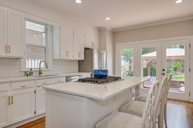 820 Barrett Ln, Augusta, GA 30909 - kitchen featuring a sink, a kitchen island, white cabinetry, backsplash, and a kitchen bar