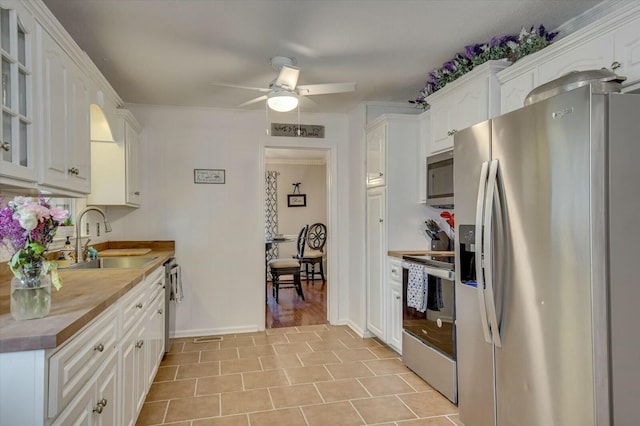 kitchen with sink, ceiling fan, light tile patterned floors, appliances with stainless steel finishes, and white cabinets