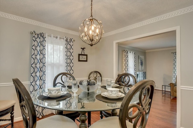 dining space with crown molding, a chandelier, wood-type flooring, and a textured ceiling