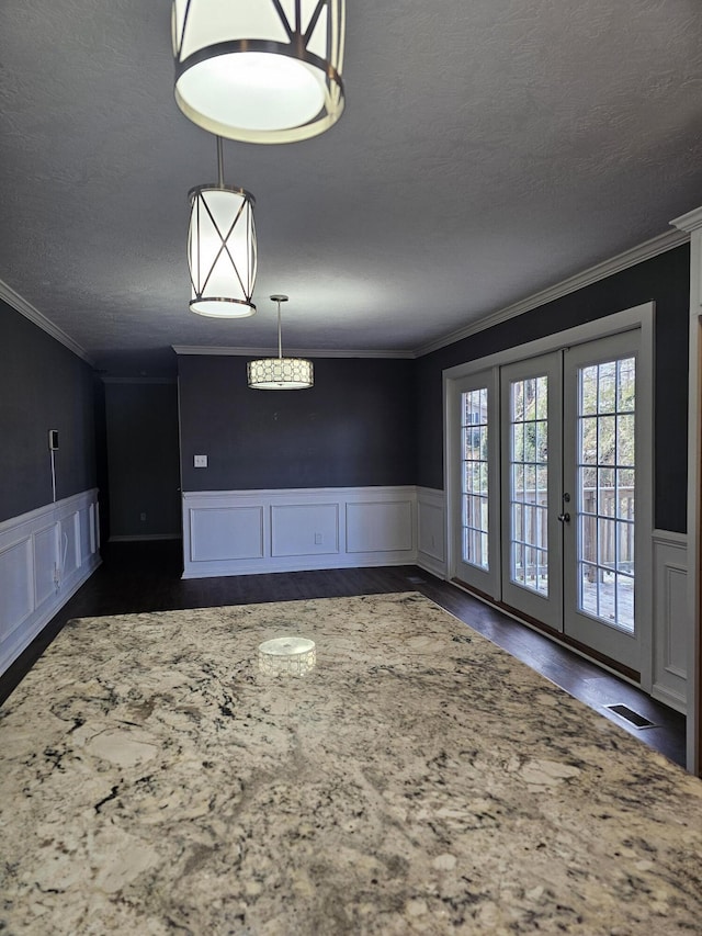 unfurnished dining area with french doors, crown molding, and a textured ceiling