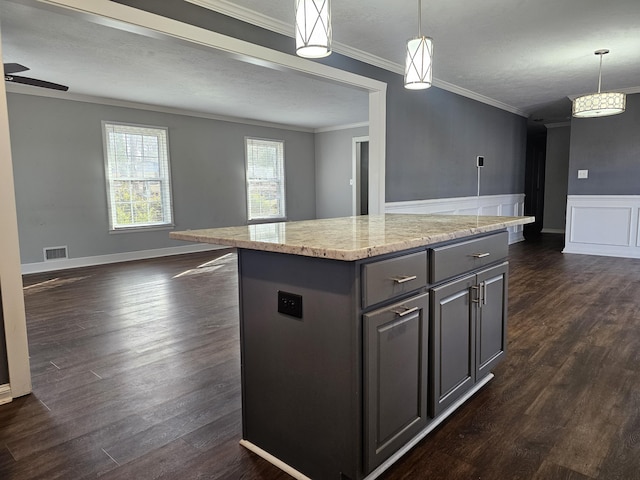 kitchen with hanging light fixtures, crown molding, light stone countertops, and a center island