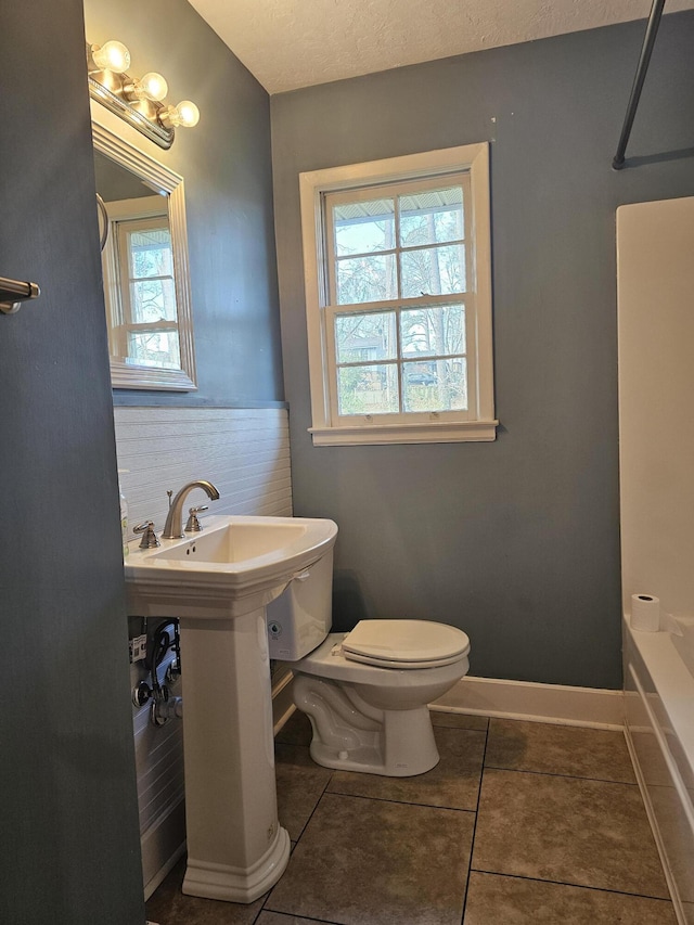 bathroom with tile patterned flooring, toilet, and a textured ceiling