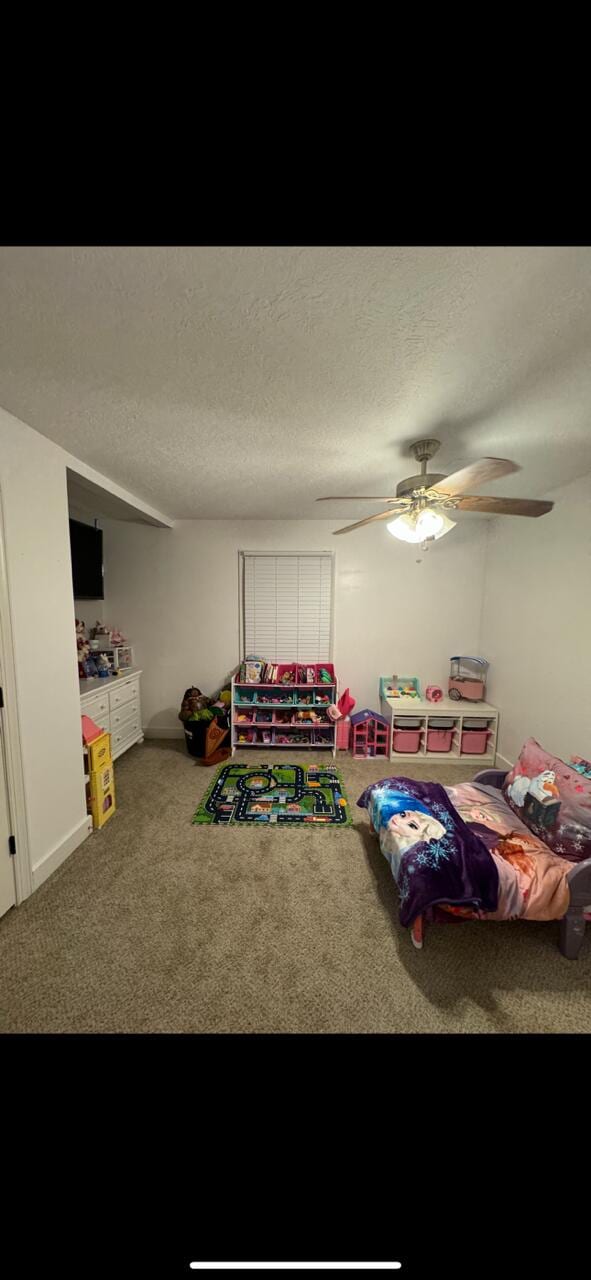 carpeted bedroom with ceiling fan and a textured ceiling