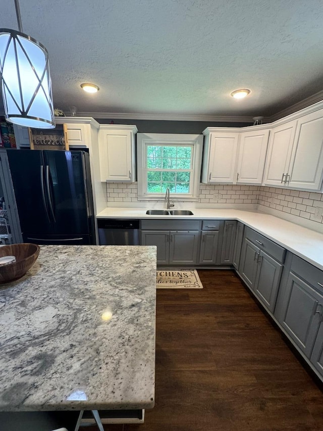 kitchen featuring sink, white cabinetry, dishwasher, black fridge, and decorative light fixtures