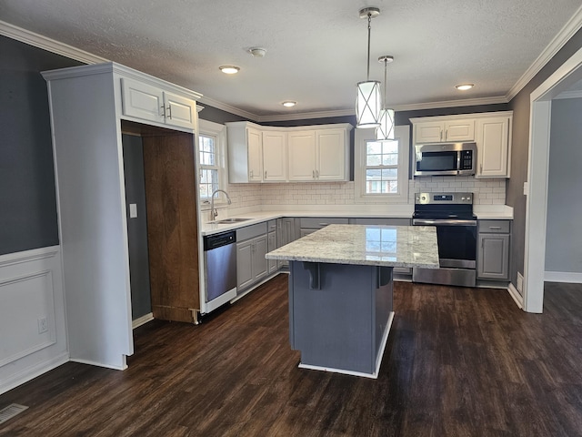 kitchen with white cabinetry, hanging light fixtures, stainless steel appliances, and a center island