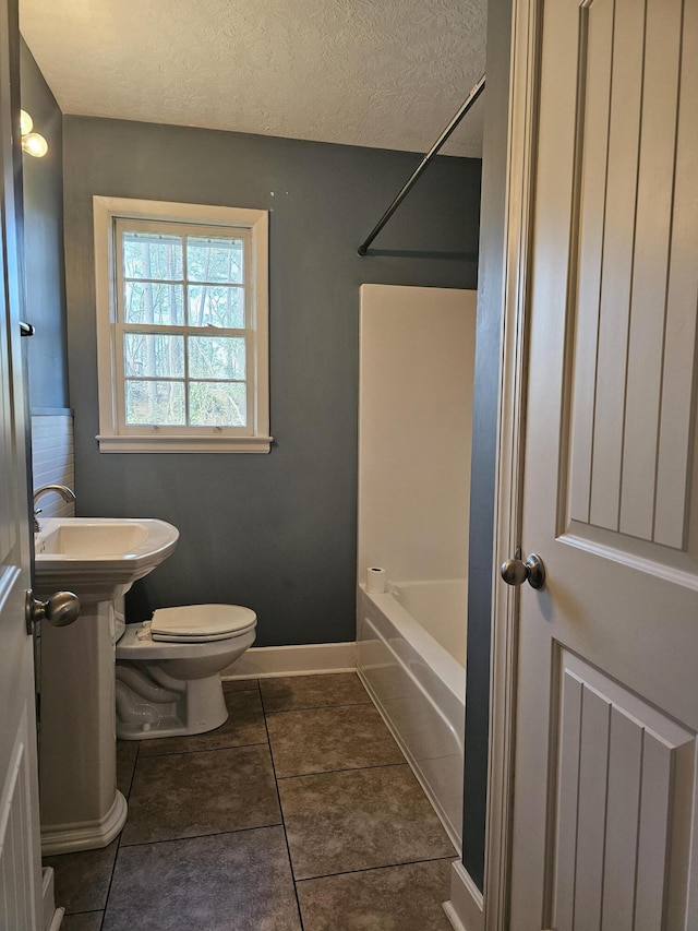 bathroom featuring shower / bath combination, a textured ceiling, tile patterned flooring, and toilet