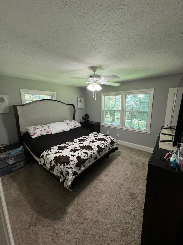 carpeted bedroom with ceiling fan and a textured ceiling