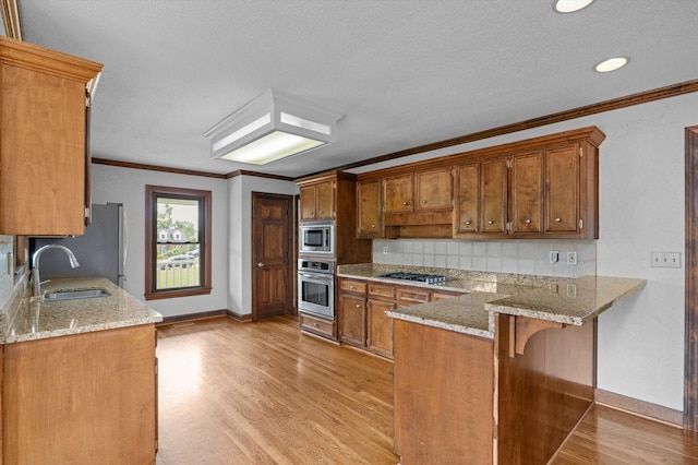 922 Windmill Ln, Evans, GA 30809 - kitchen with appliances with stainless steel finishes, a sink, brown cabinetry, baseboards, and crown molding
