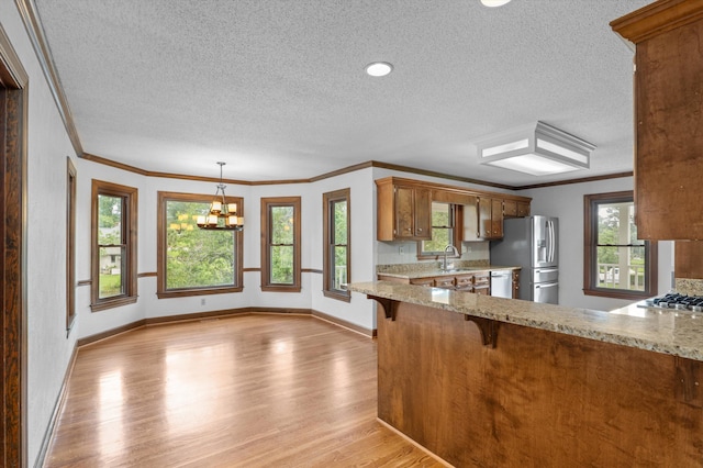 922 Windmill Ln, Evans, GA 30809 - kitchen with appliances with stainless steel finishes, a textured ceiling, light wood-style floors, crown molding, and brown cabinetry