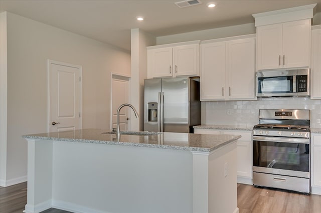 2015 Saylor Ln, Grovetown, GA 30813 - kitchen featuring stainless steel appliances, a sink, light wood finished floors, white cabinets, and a center island with sink
