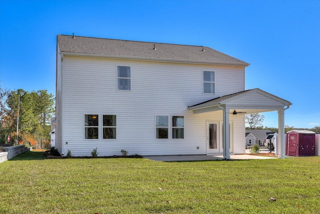 back of property featuring ceiling fan, a storage shed, a patio area, and a yard