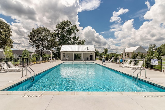 pool featuring an outbuilding, a patio area, and fence