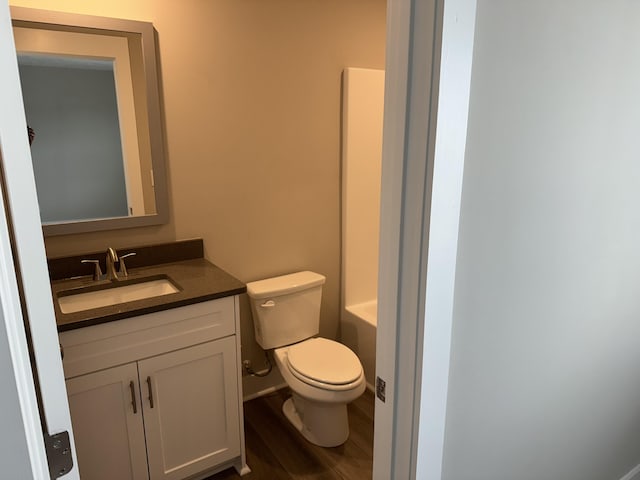 full bath featuring a tub to relax in, a shower, toilet, wood finished floors, and vanity