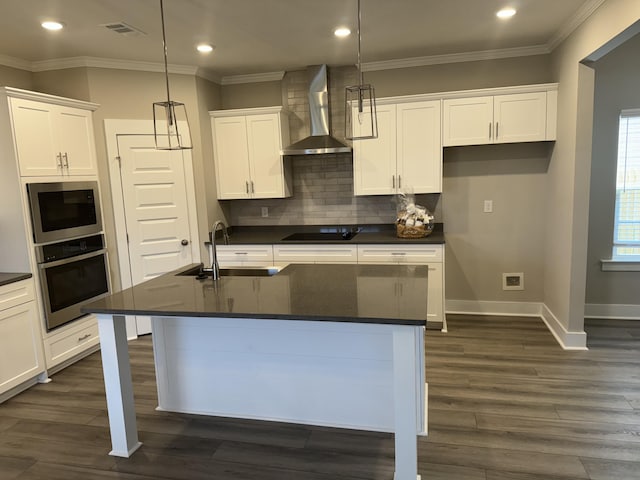 kitchen featuring stainless steel appliances, a sink, visible vents, wall chimney range hood, and dark countertops