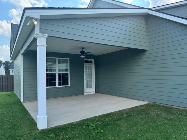 property entrance with a lawn, ceiling fan, fence, and a patio