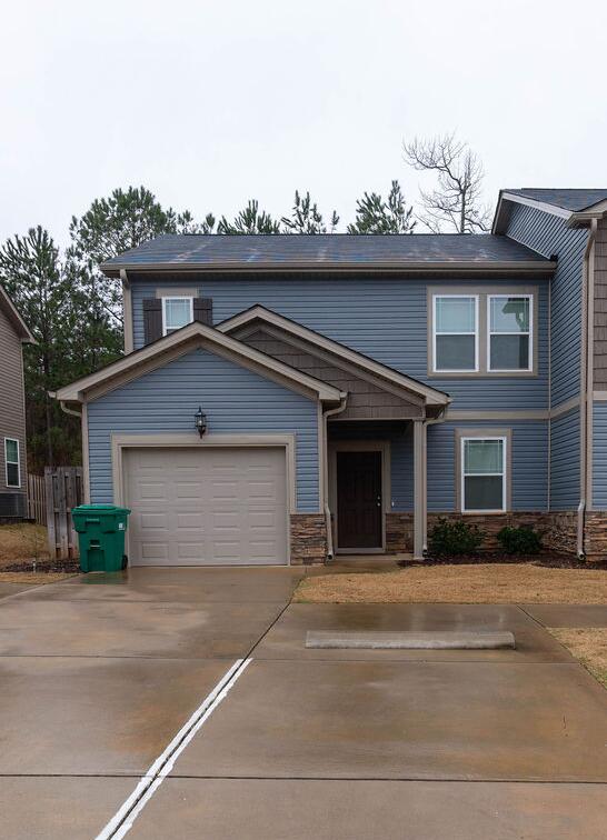 view of front of home featuring concrete driveway, stone siding, and an attached garage