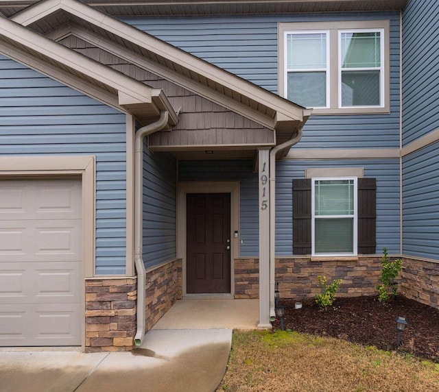 entrance to property featuring stone siding and an attached garage