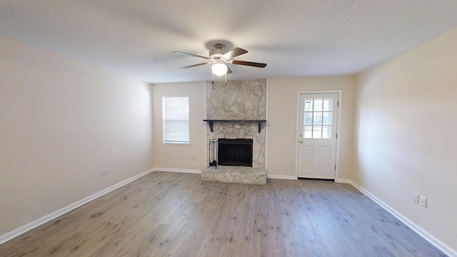 unfurnished living room featuring baseboards, a fireplace, wood finished floors, and a ceiling fan