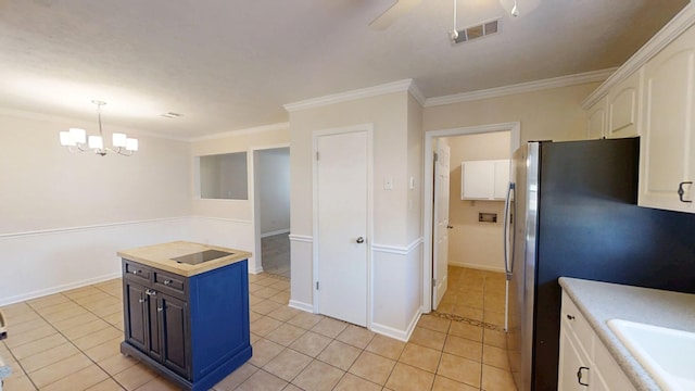 kitchen featuring light tile patterned flooring, white cabinetry, freestanding refrigerator, and ornamental molding