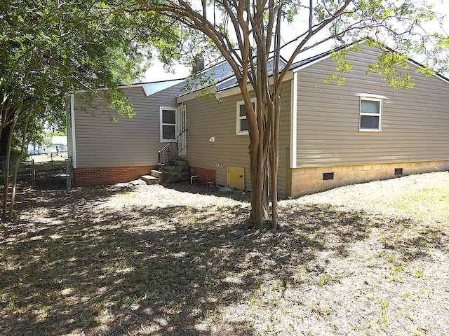 rear view of house featuring crawl space, entry steps, and fence