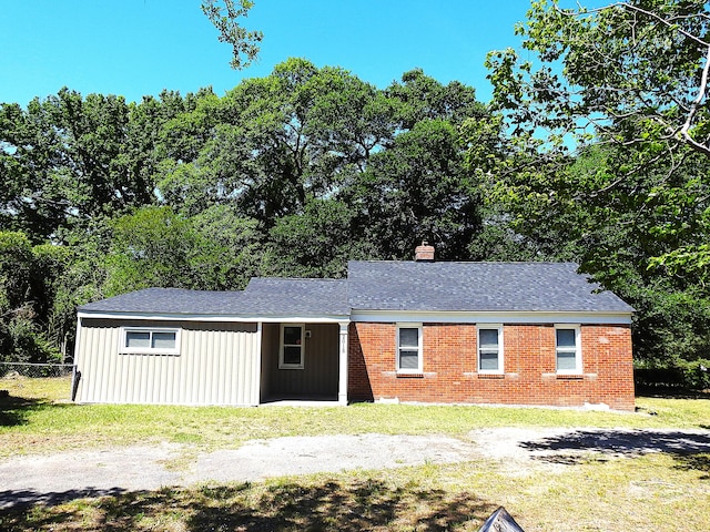 view of front of house featuring a chimney, brick siding, roof with shingles, and board and batten siding