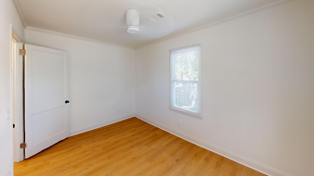 spare room featuring ornamental molding, light wood-style flooring, and baseboards