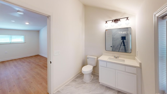 bathroom featuring toilet, vanity, baseboards, and recessed lighting