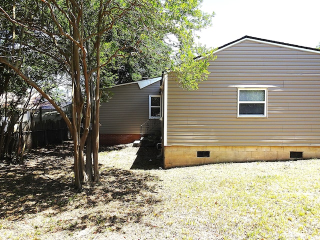 view of home's exterior with crawl space and fence