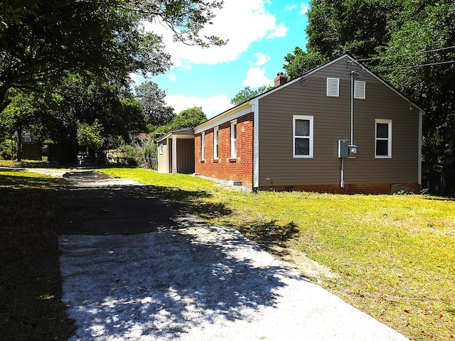 view of side of property featuring crawl space, a lawn, a chimney, and driveway
