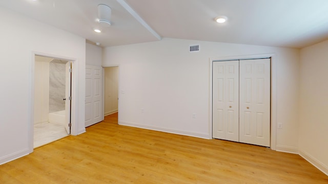 unfurnished bedroom with light wood-type flooring, vaulted ceiling, ensuite bath, baseboards, and a closet