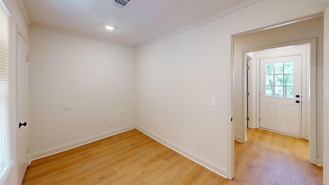 empty room featuring light wood finished floors, ornamental molding, and baseboards