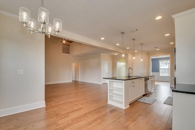 kitchen with pendant lighting, a notable chandelier, an island with sink, and white cabinets